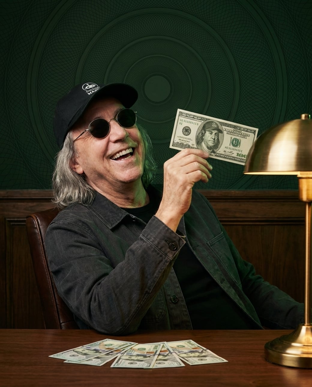 Franklin at his desk, laughing, holding a hundred-dollar bill